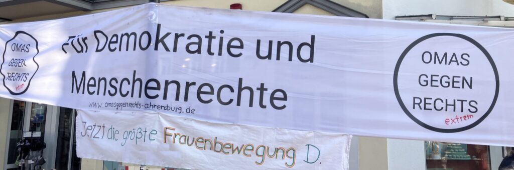 Foto mit Banner. Bannertext: Für Demokratie und Menschenrechte. Omas gegen Rechts. Jetzt die größte Frauenbewegung in D.